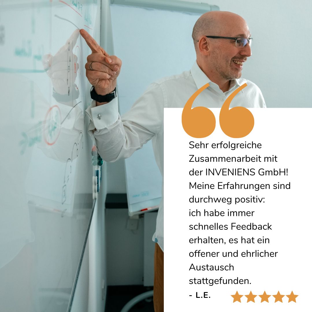 Joachim Trenz zeigt lächelnd auf ein Whiteboard, darunter sieht man eine Google Bewertung