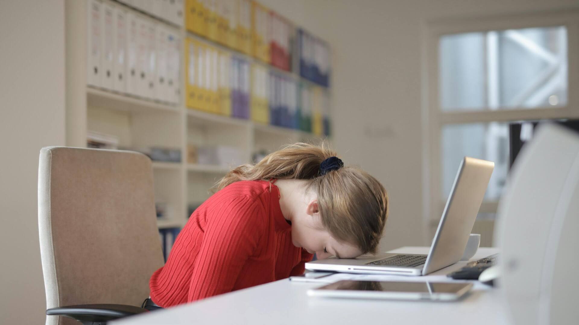 Herausforderungen für Insolvenzverwalter: Stress und Wettlauf gegen die Zeit - Konsequenzen und Lösungen für Kanzleien Eine Insolvenzverwalterin ist angestrengt und lehnt mit ihrem Kopf auf einem Laptop