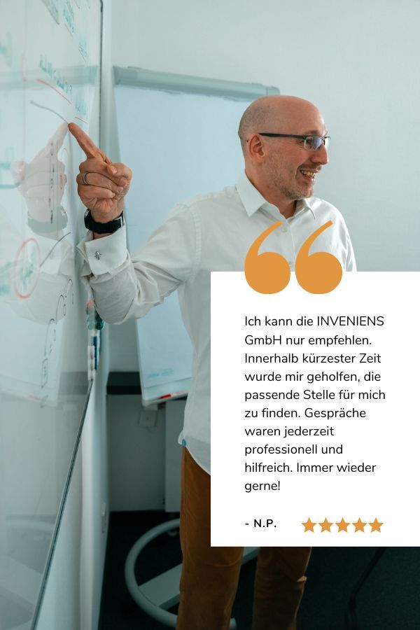 Joachim Trenz zeigt lächelnd auf ein Whiteboard, darunter sieht man eine Google Bewertung