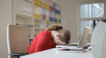 Insolvenzverwalterin lehnt angestrengt mit ihrem Kopf auf dem Laptop